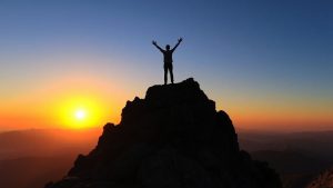 Persoană pe un vârf de munte la răsărit